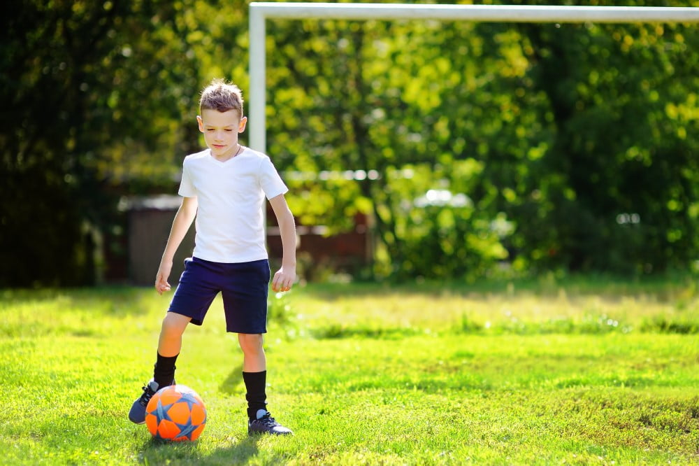 Dreng der spiller fodbold i sin have